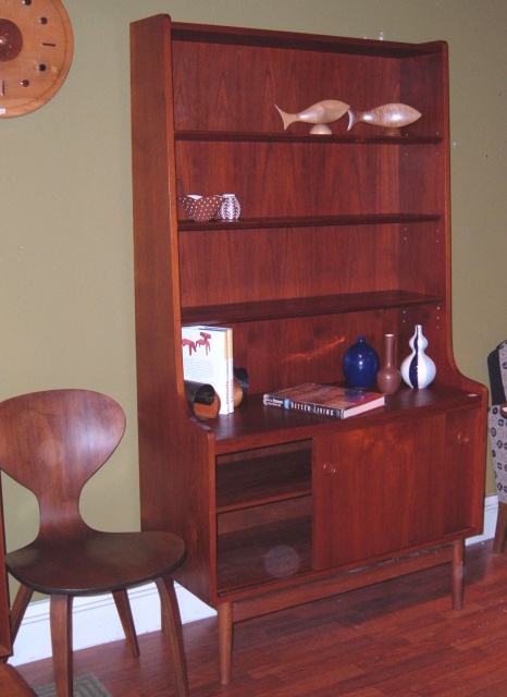 Danish modern teak bookshelf and lower storage area with shelf and slider doors. Overall measurements: 42"W x 72"H, (3) adjustable  8" shelves on upper cabinet.  Previous owner has made small incisions for telephone jacks on rear panel-but can be hidden when lower shelf is 4th in position.  SOLD